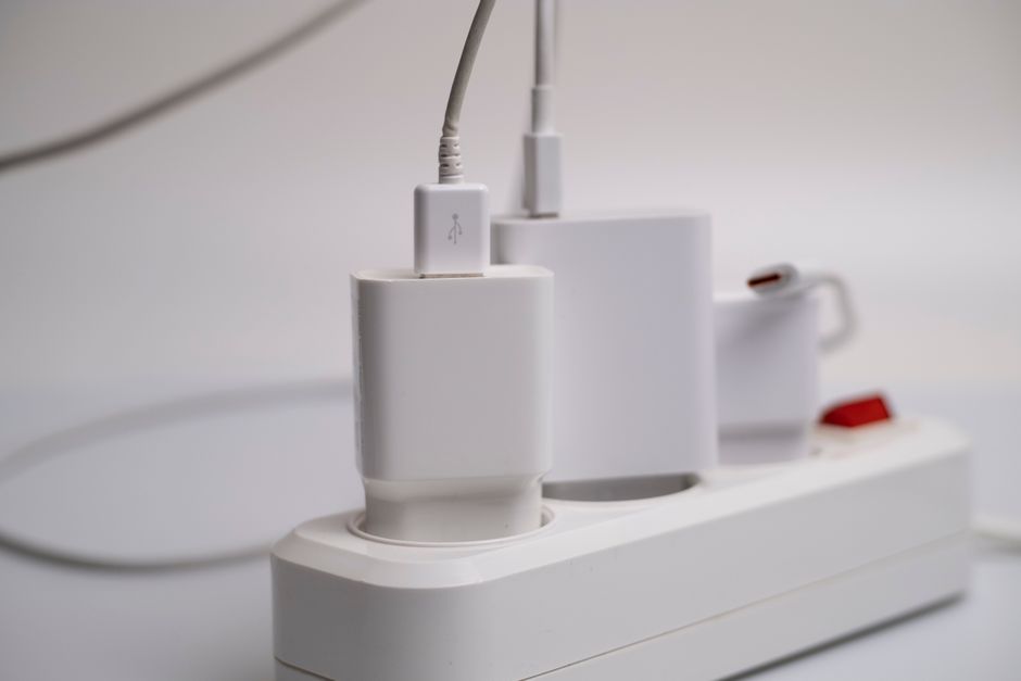 Varios cargadores y adaptadores enchufados a la vez en una regleta blanca
