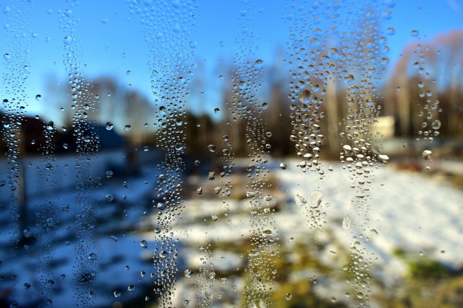 Gotas de agua en el cristal de una ventana con un paisaje nevado al fondo