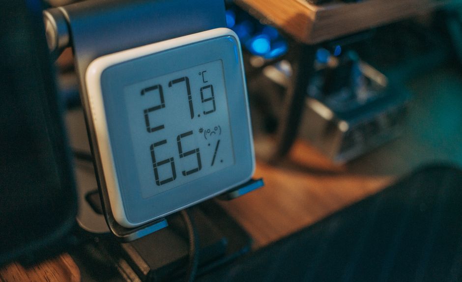 Termohigrómetro digital sobre un escritorio que marca 27,9 °C y 65 % de humedad