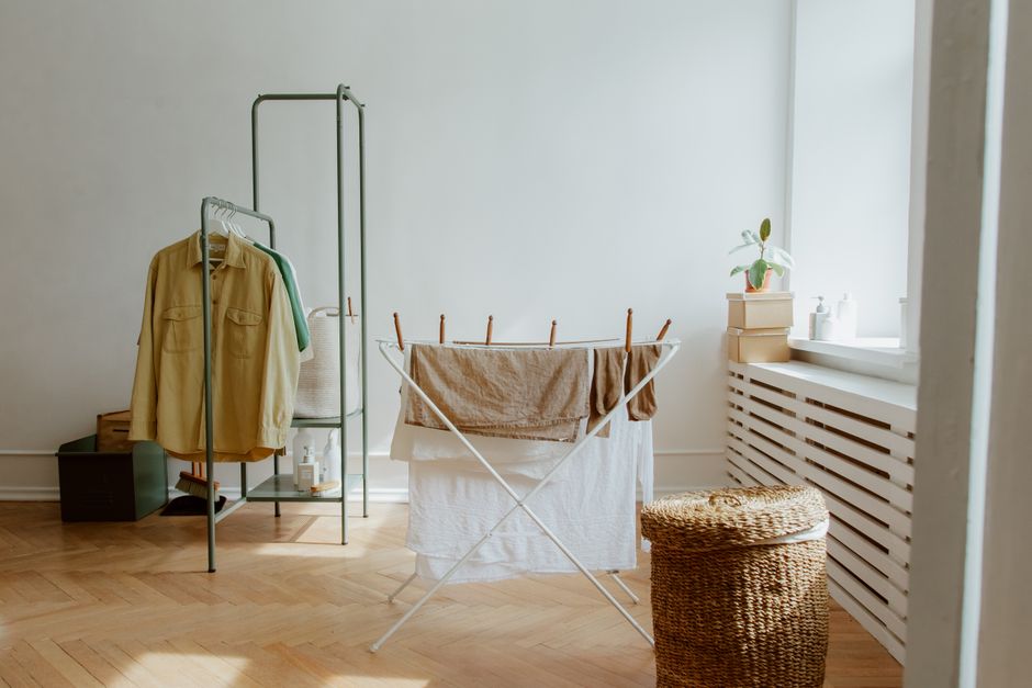 Ropa tendida en un tendedero plegable dentro de una habitación luminosa con suelo de madera