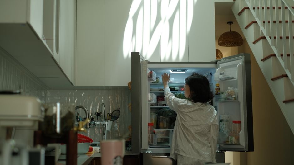Persona frente a un frigorífico abierto en una cocina con luz natural