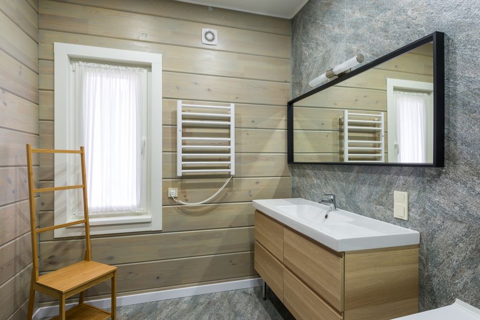 Baño con un toallero de barras metálico junto a la ventana, bajo un espejo