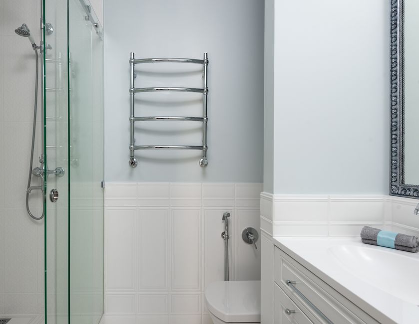 Baño con mampara de ducha y un toallero cromado en la pared, junto a la bañera