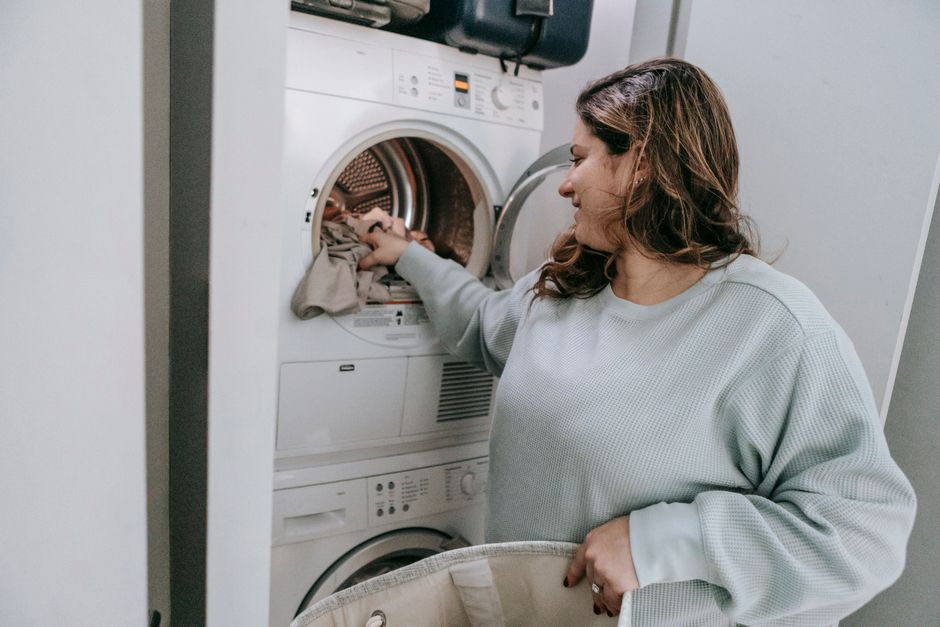 Mujer cargando ropa en una lavadora doméstica en casa